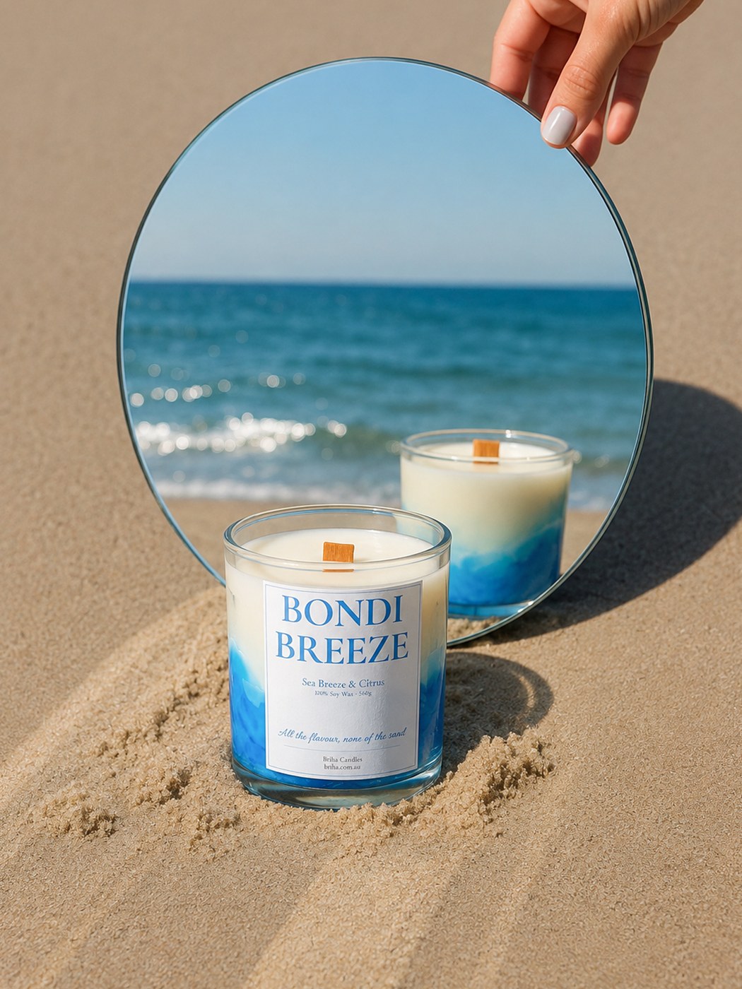 Bondi Breeze candle in sand with a round mirror reflecting the ocean