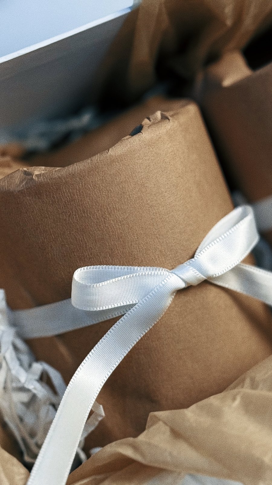 Close-up of a gift-wrapped Briha candle tied with white ribbon