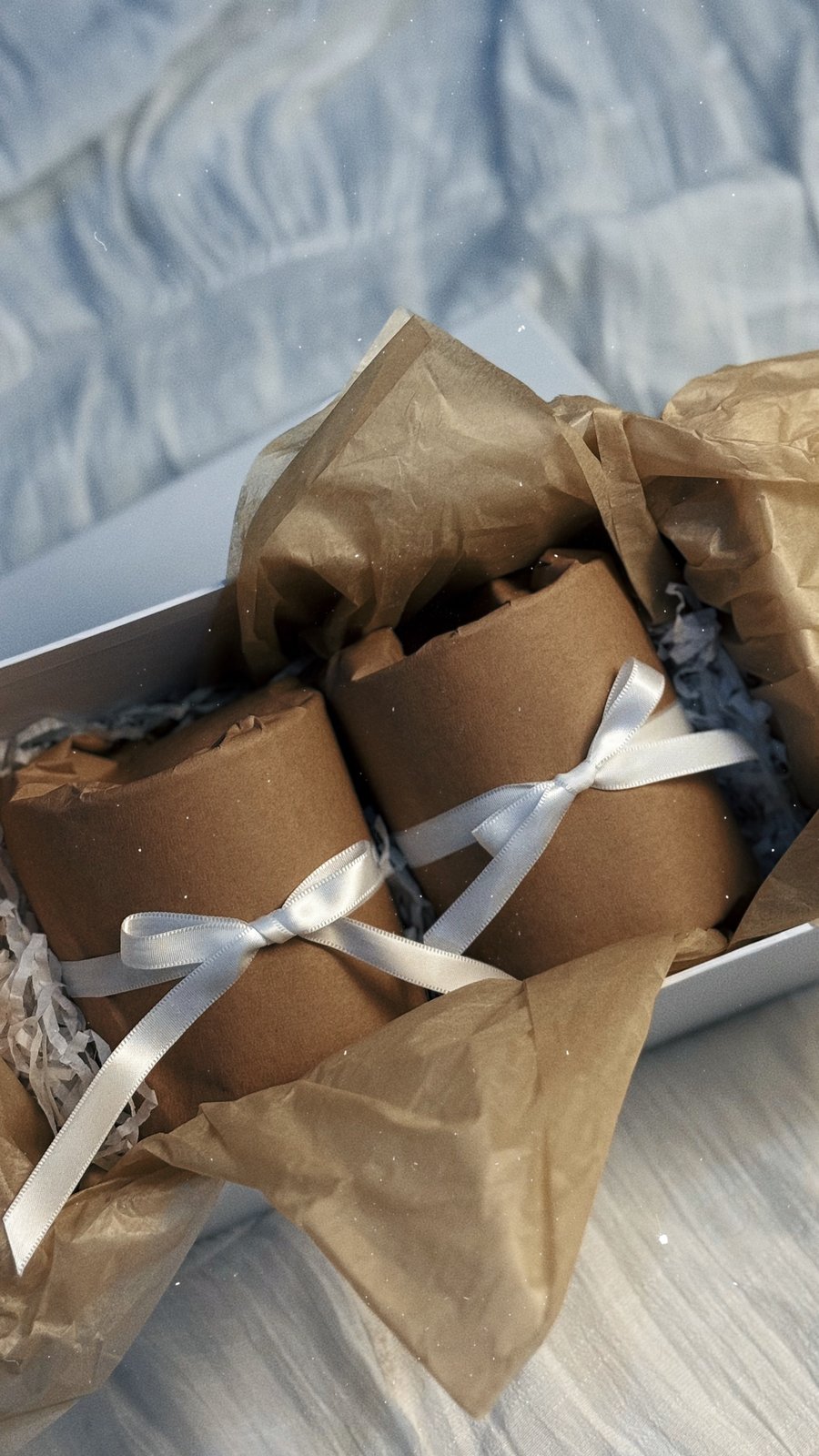 Two Briha candles wrapped in kraft paper and tied with ribbon inside a gift box